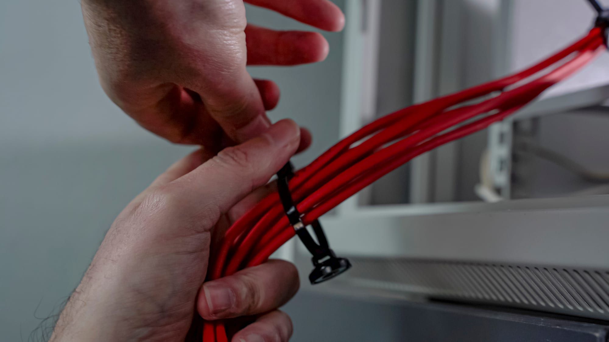 A bundle of red cables being zip-tied to a magnetic mount