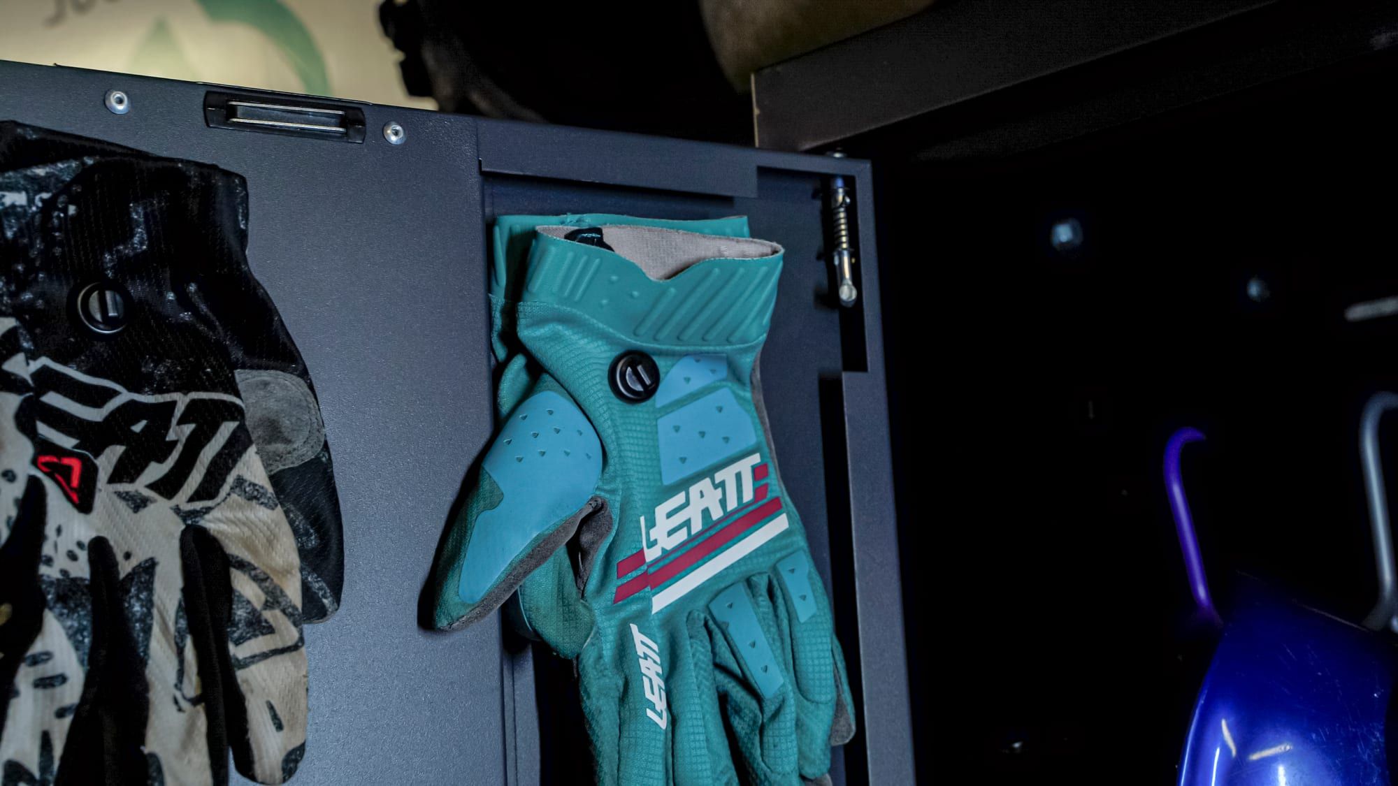 Gloves hanging from zip-tie loops on magnetic mounts inside a steel cabinet
