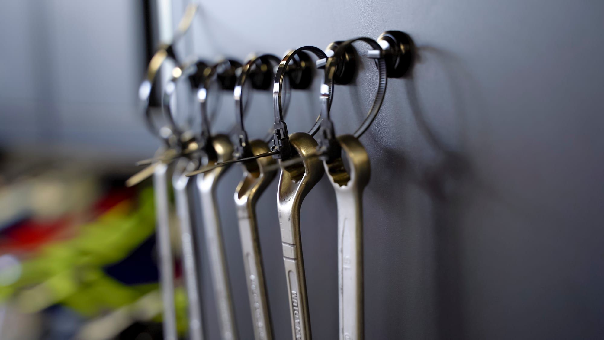 Wrenches hanging from magnetic mounts on a steel garage cabinet